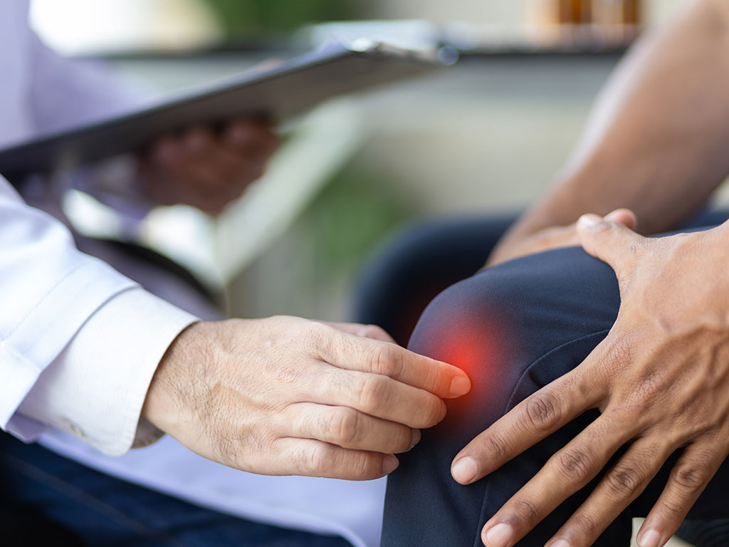Orthopäde erklärt Symptome von Kniebeschwerden bei Patient in OCS Düsseldorf