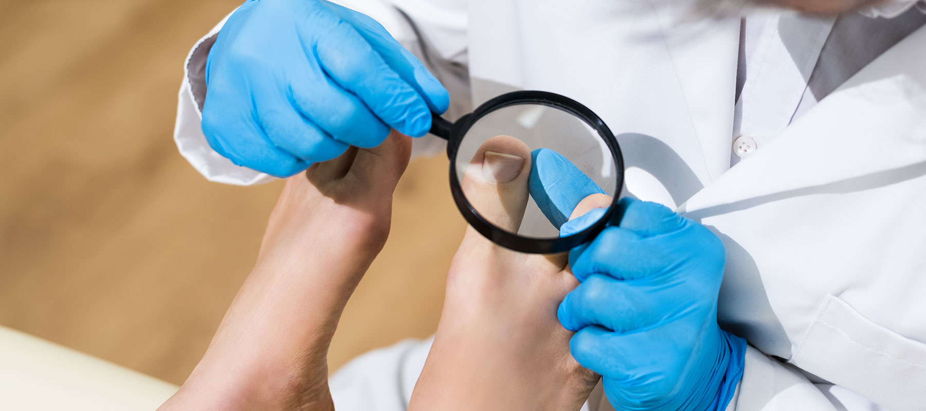 Orthopäde untersucht großen Zeh mit Lupe bei OCS Düsseldorf
